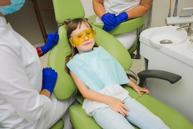 Foto dentista con niña en silla