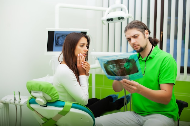Dentista no consultório odontológico conversando com paciente do sexo feminino e se preparando para o tratamento