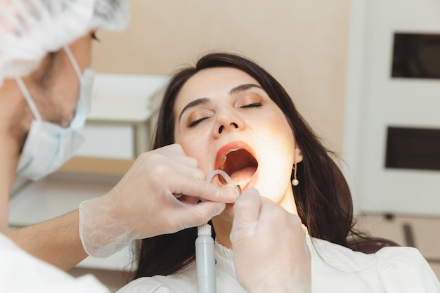 Dentista y paciente en el consultorio dental El médico trata los dientes de una mujer joven con un taladro Higiene y dientes sanos