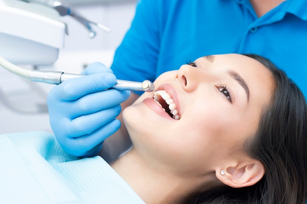 Foto dentista y paciente en el consultorio dental. mujer con dientes examinados por dentistas