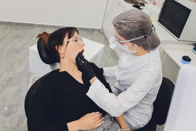 Dentista y paciente eligiendo tratamiento en una consulta con equipo médico en segundo plano