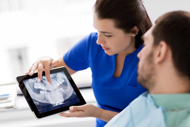 Foto dentista y paciente con radiografía de dientes en tablet pc