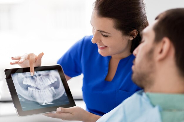 dentista y paciente con radiografía de dientes en tablet pc