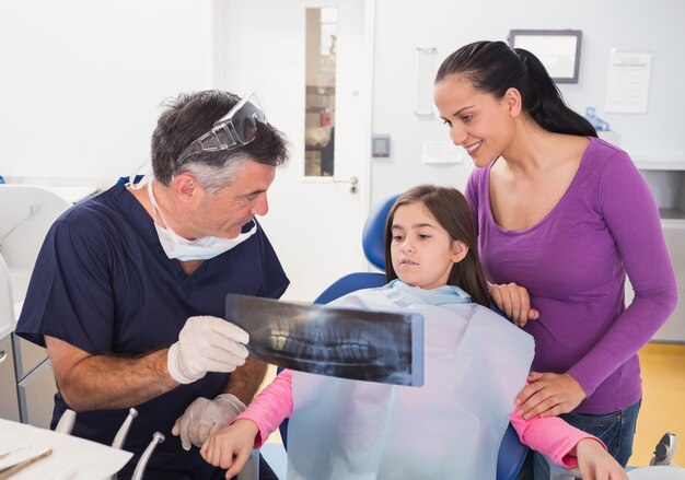 Dentista pediatra explica a la paciente joven y su madre la radiografía