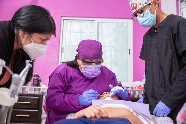 Dentista pediatra mexicano explicando ao jovem paciente e sua mãe