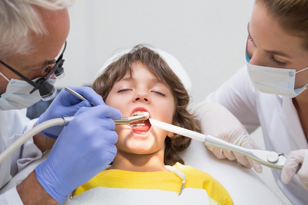 Dentista pediátrico y asistente examinando los dientes de un niño pequeño