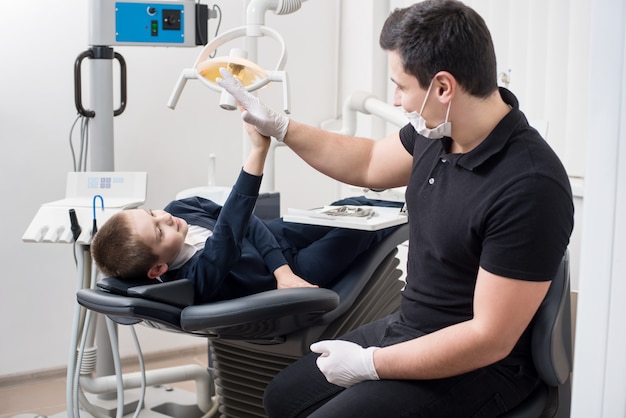 Dentista pediátrico da cinco niños en consultorio dental