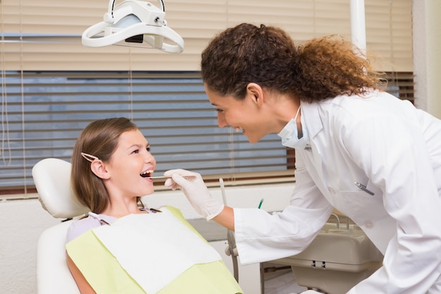 Dentista pediátrico examinando los dientes de una niña en la silla de los dentistas