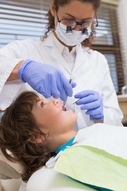 Dentista pediátrico examinando los dientes de un niño pequeño en la silla de dentistas