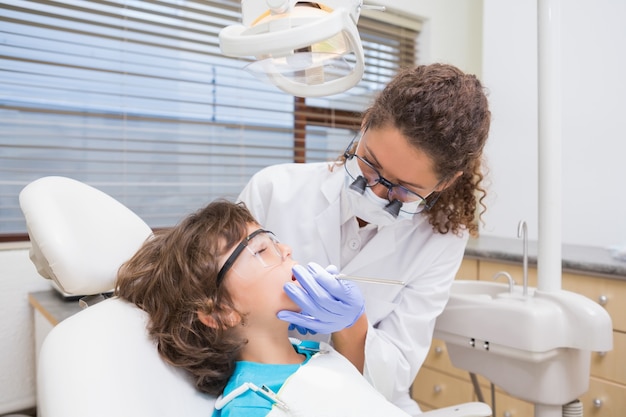 Dentista pediátrico examinando los dientes de un niño pequeño en la silla de dentistas