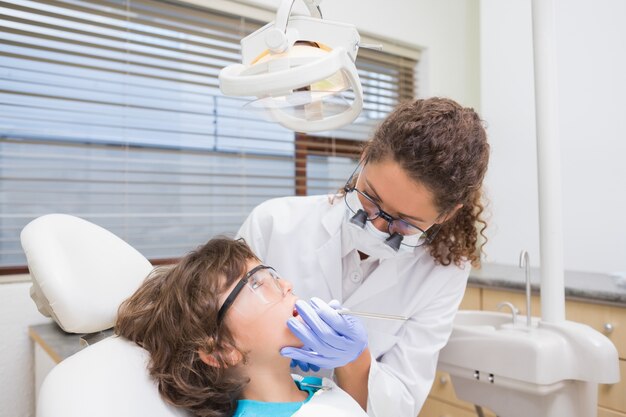 Dentista pediátrico examinando los dientes de un niño pequeño en la silla de dentistas