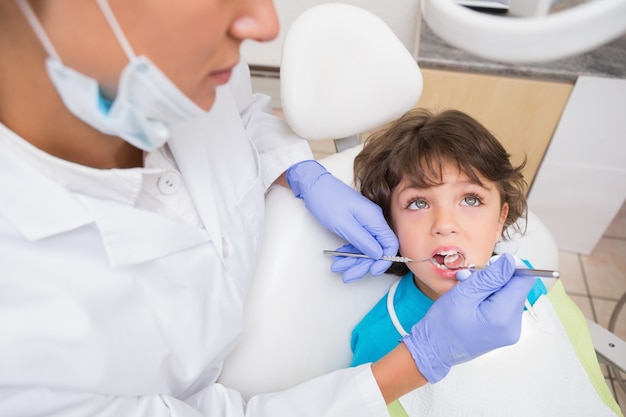 Dentista pediátrico examinando los dientes de un niño pequeño en la silla de dentistas