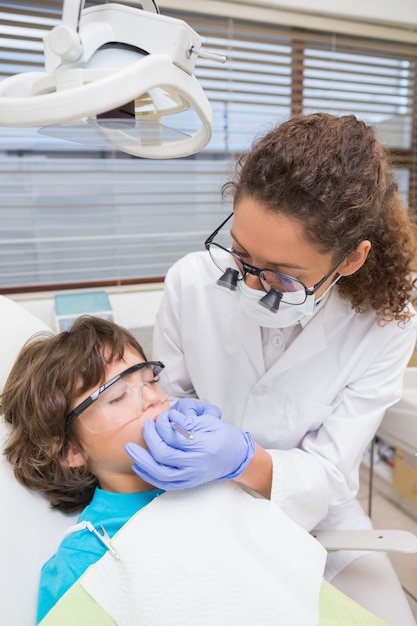 Dentista pediátrico examinando los dientes de un niño pequeño en la silla de dentistas