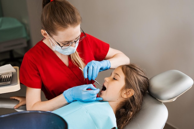 Dentista pediátrico y niña alegre sonriendo en odontología El niño sonríe en la consulta con el dentista Publicidad creativa para odontología