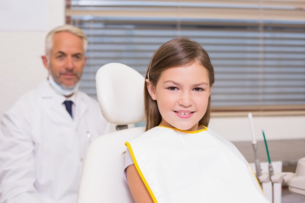 Dentista pediátrico y niña sonriendo a la cámara