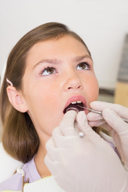 Dentista pediátrico que examina los dientes de las niñas en la silla de los dentistas