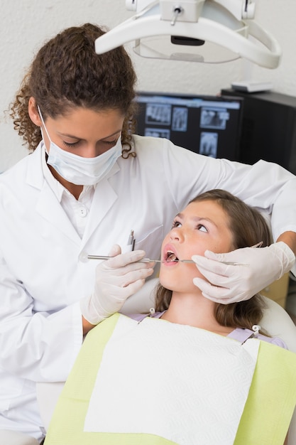 Dentista pediátrico que examina los dientes de un paciente en la silla de los dentistas