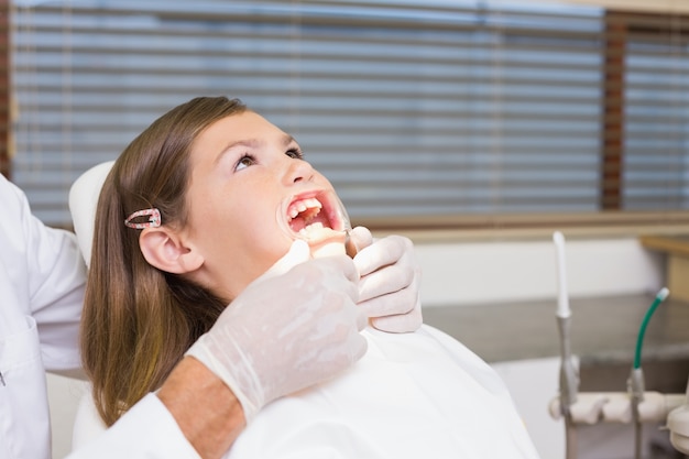 Dentista poniendo retractor de boca en la niña