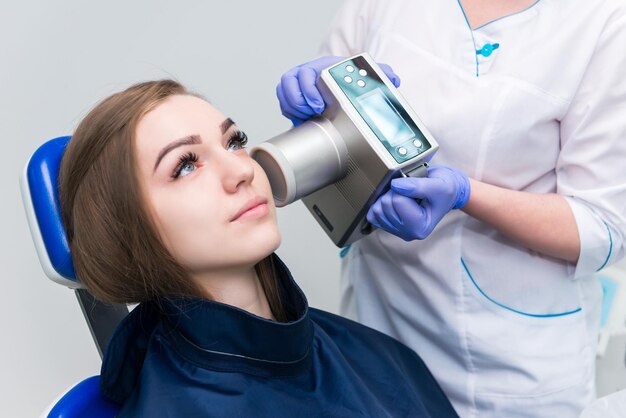 El dentista se prepara para hacer una imagen de rayos X de dientes para una niña en una clínica dental