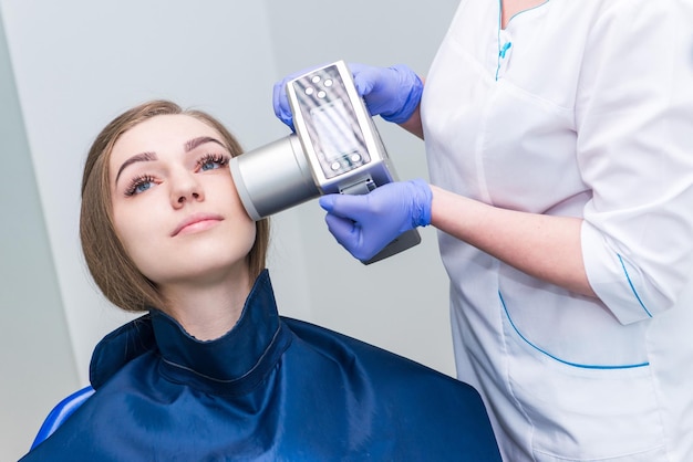 El dentista se prepara para hacer una imagen de rayos X de dientes para una niña en una clínica dental