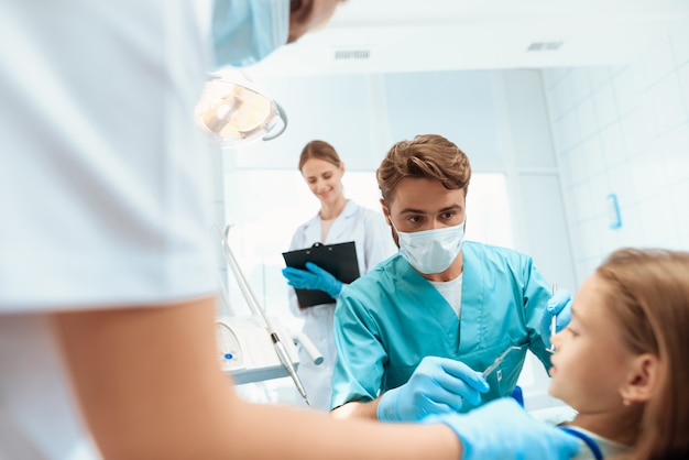 Un dentista se prepara para tratar los dientes de una niña.