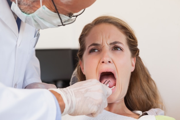 Dentista prestes a puxar um dente de pacientes aterrorizados