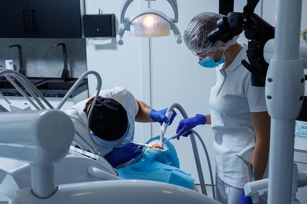 Un dentista profesional examina los dientes de un paciente con equipo dental y sostiene instrumentos dentales cerca de su boca Dentista Cabina dental