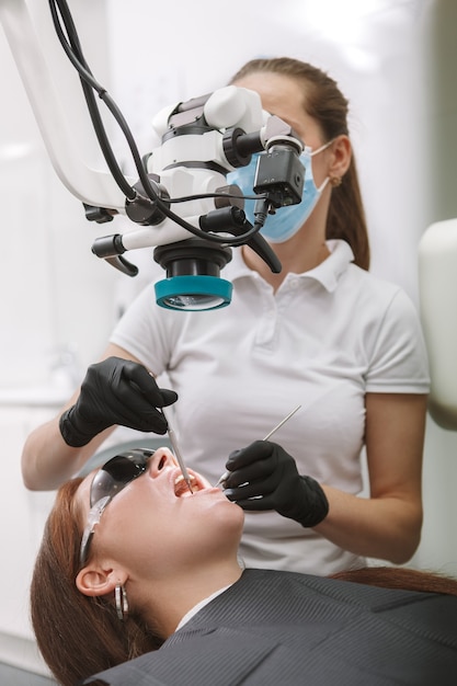 Dentista profesional con microscopio dental, trabajando en su clínica