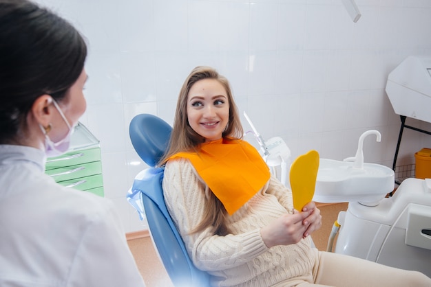 Un dentista profesional trata y examina la cavidad bucal de una niña embarazada en un consultorio dental moderno. Odontología