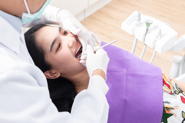 Dentista que controla los dientes de la mujer paciente