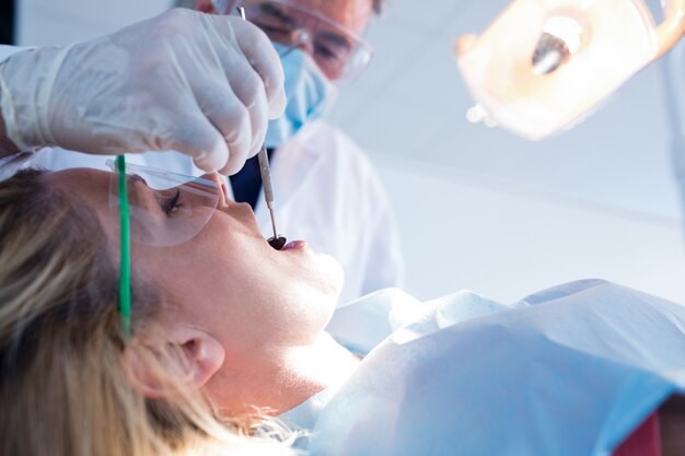 Dentista que examina los dientes de un paciente bajo luz brillante