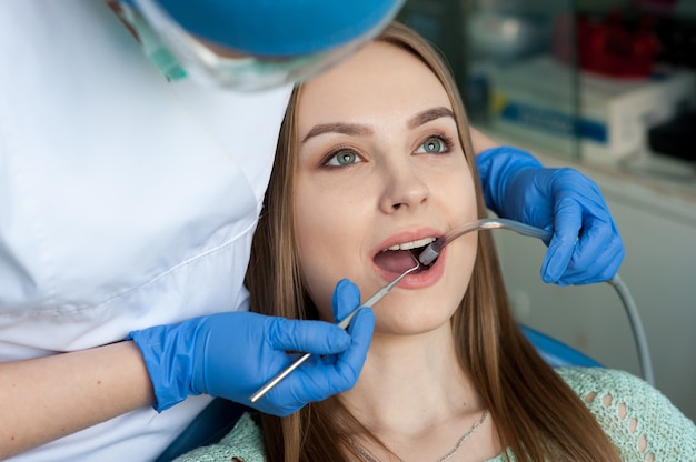 Dentista que examina os dentes de um paciente na clínica odontológica.