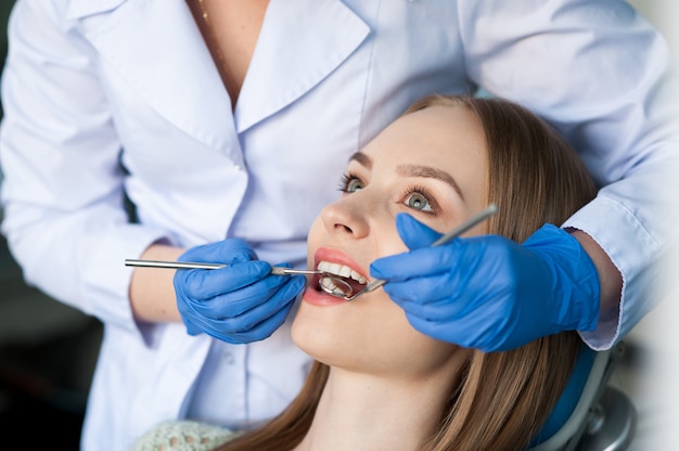 Dentista que examina os dentes de um paciente na clínica odontológica.