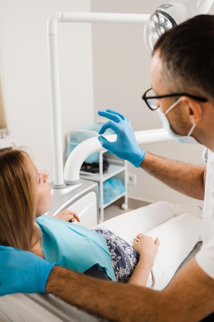 Dentista que muestra el implante de dientes de chapa dental a una paciente en una clínica dental Consulta de odontología con el dentista sobre la implantación y el blanqueamiento dental