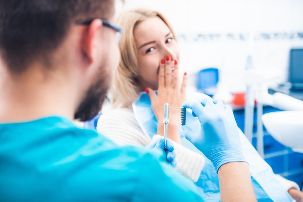 Dentista que muestra el modelo de implante gris al paciente