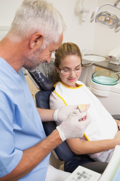 Dentista que muestra paciente modelo de dientes