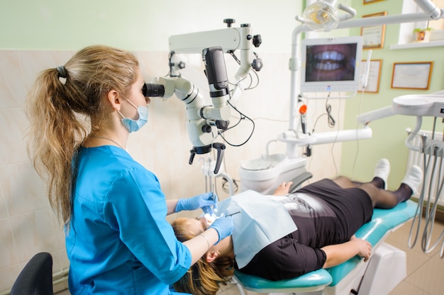 Dentista que trabaja con el microscopio en la oficina moderna del dentista