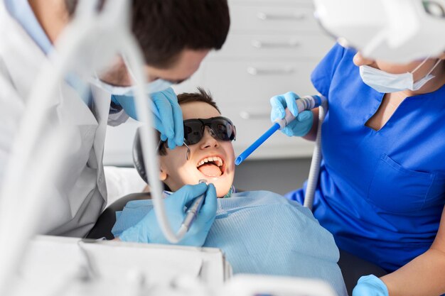 Foto dentista que trata os dentes das crianças na clínica dentária