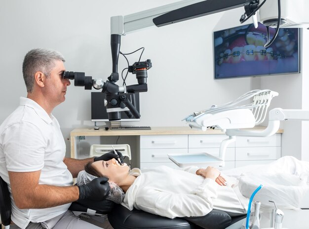 Dentista que usa microscopio dental que trata los dientes del paciente en la oficina de la clínica dental Medicina odontología y concepto de atención médica Equipo dental