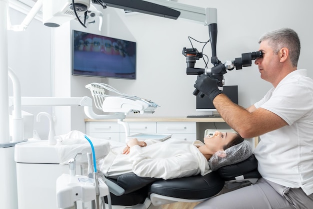 Dentista que usa microscopio dental que trata los dientes del paciente en la oficina de la clínica dental Medicina odontología y concepto de atención médica Equipo dental