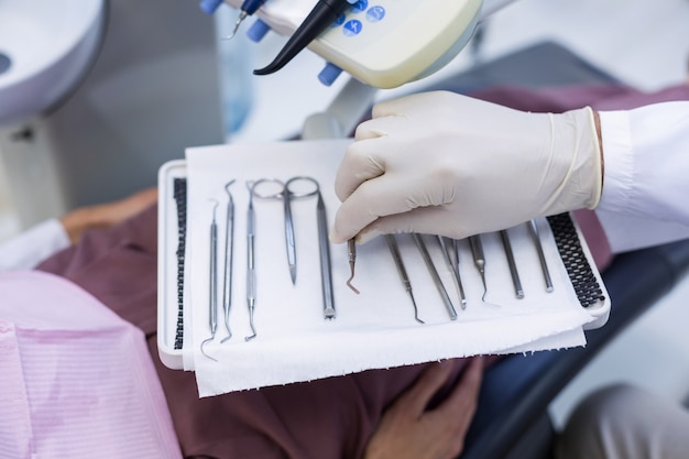 Dentista recogiendo herramientas dentales para examinar a un paciente