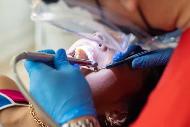 Dentista revisando los dientes de una mujer en una oficina bien iluminada