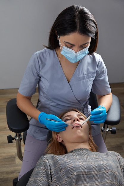 Dentista revisando los dientes de una paciente con espejo dental