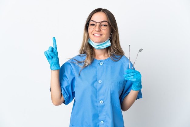 Dentista romena segurando ferramentas isoladas em uma parede rosa apontando para uma ótima ideia