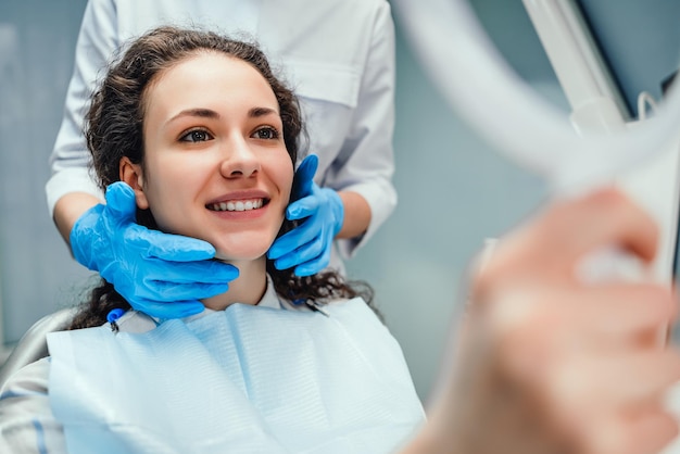 Foto un dentista está sentado uno al lado del otro mujer sonriendo paciente feliz y dentista