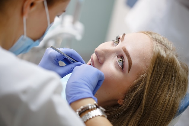 Dentista de sexo femenino que controla los dientes pacientes de la muchacha