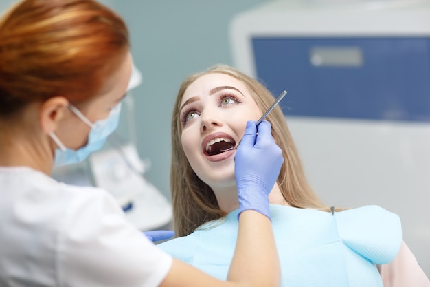 Dentista de sexo femenino que controla los dientes pacientes de la muchacha
