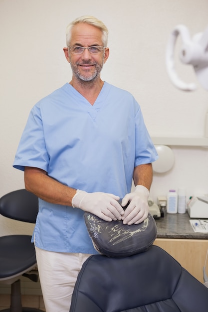 Dentista sonriendo a la cámara al lado de la silla