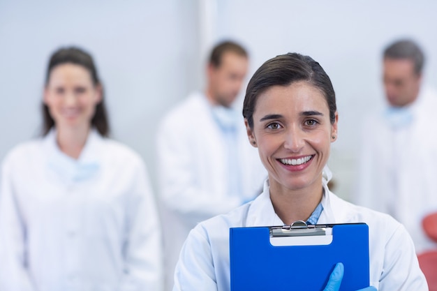 Dentista sonriente de pie en la clínica dental