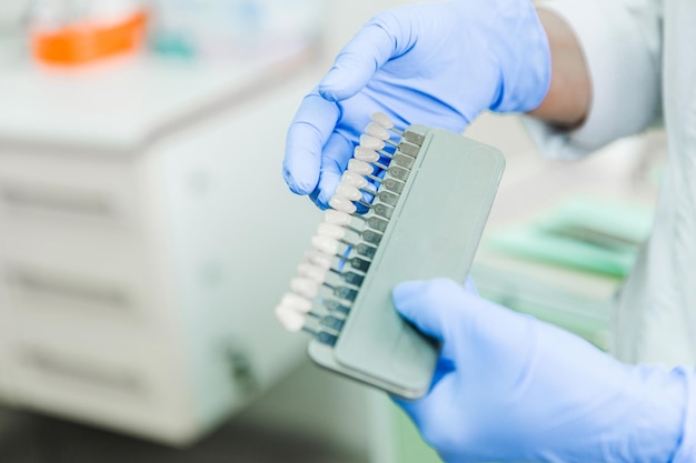 Dentista sosteniendo una guía de sombra de dientes en la clínica